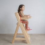 Niño sentado en silla de comer evolutiva Montessori con postura correcta a 90 grados en cadera, rodillas y tobillos durante la alimentación