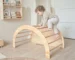 Bebé trepando en arco Pikler de madera en habitación Montessori promoviendo movimiento libre y desarrollo motor temprano
