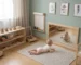 Bebé explorando habitación Montessori con espejo seguro de madera, juguetes accesibles y mobiliario infantil diseñado para estimular autonomía y desarrollo sensorial.