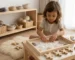 Niña pequeña explorando conchas y materiales sensoriales naturales en ambiente Montessori preparado desarrollando imaginación desde experiencias concretas y reales